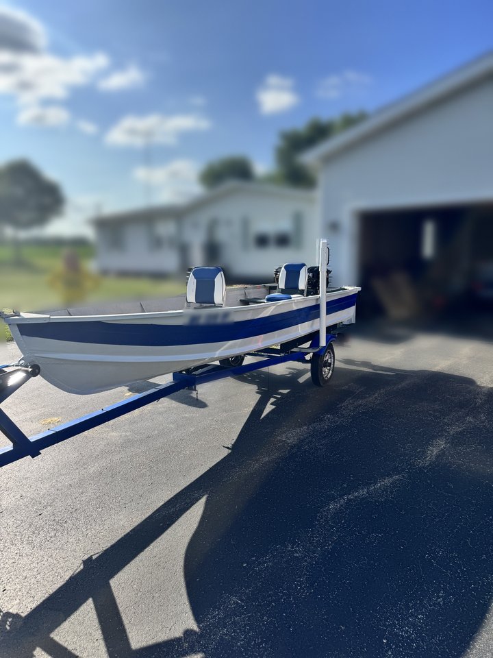 The restored StarCraft in new blue and white paint on its restored blue trailer, with a new outboard motor