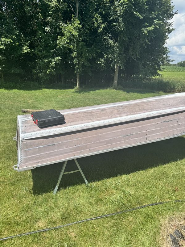 StarCraft aluminum hull upside down on sawhorses with the old finish being stripped